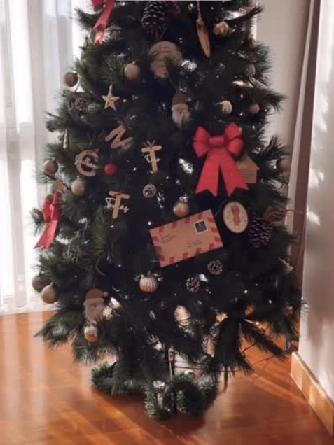 Árvore de Natal com o envelope da carta do Pai Natal entre os enfeites