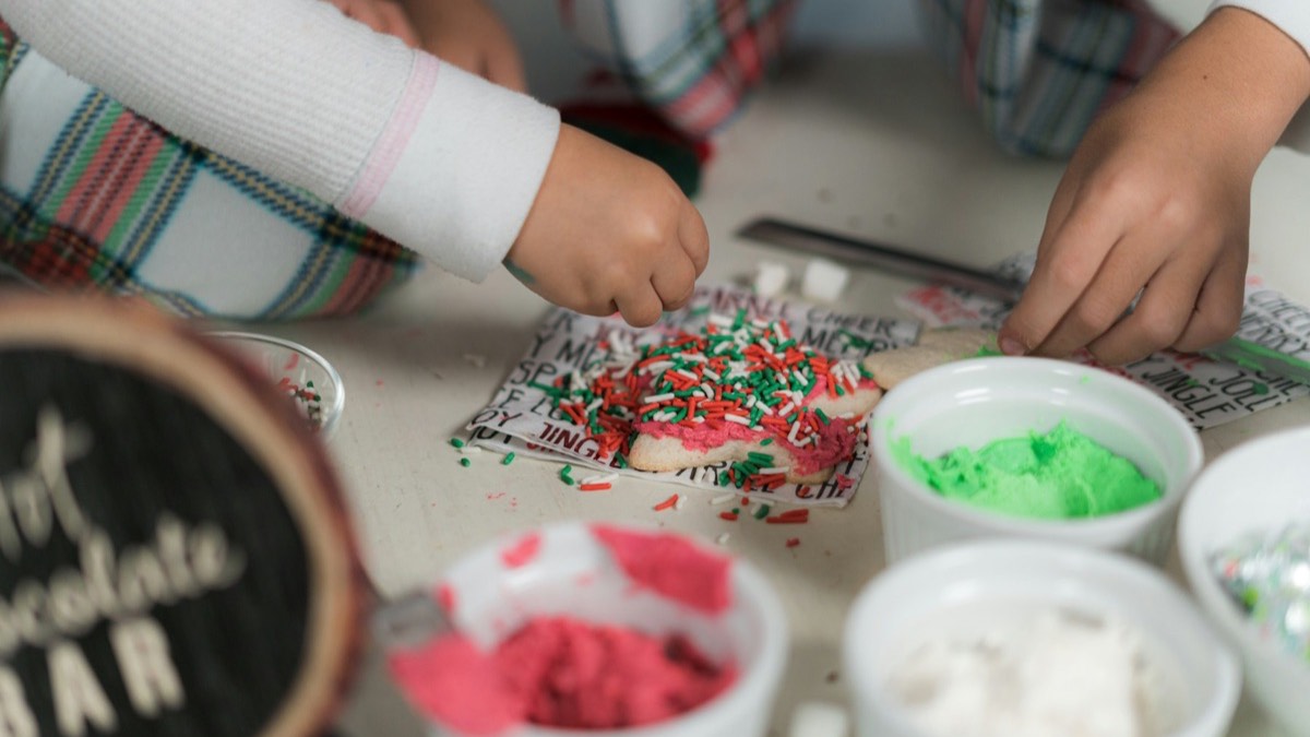 Mãos de crianças a decorar bolachas de Natal