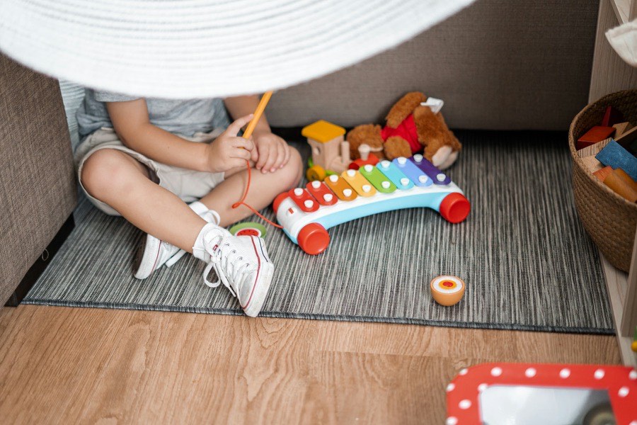Criança a brincar com um xilofone de brinquedo numa tenda