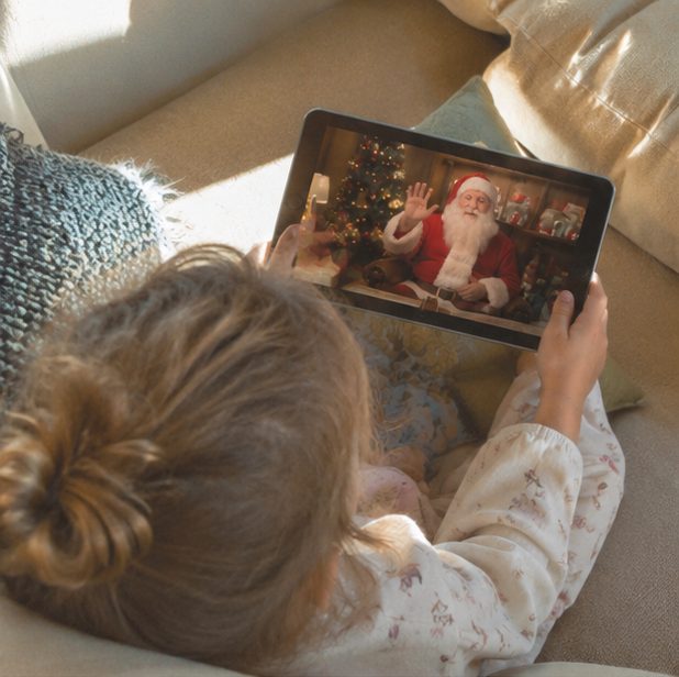 Criança deitada no sofá a ver a mensagem de vídeo do Pai Natal num tablet